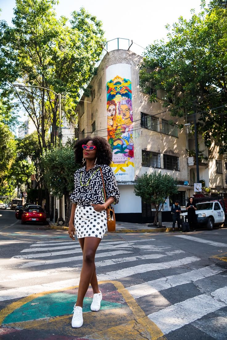 a woman is crossing the street in front of a building with a mural on it