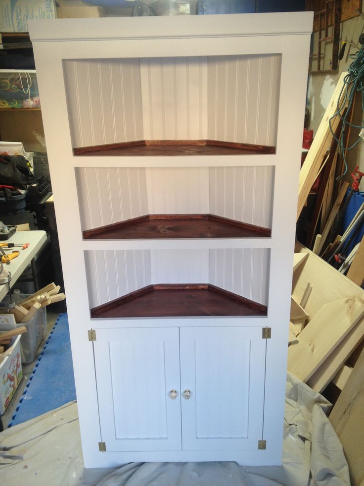 a white bookcase with three shelves and two cupboards on top of each shelf