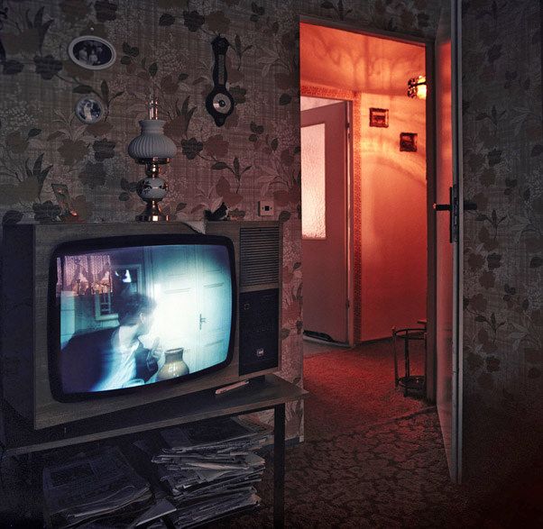 an old fashioned television sitting on top of a table in a room with floral wallpaper