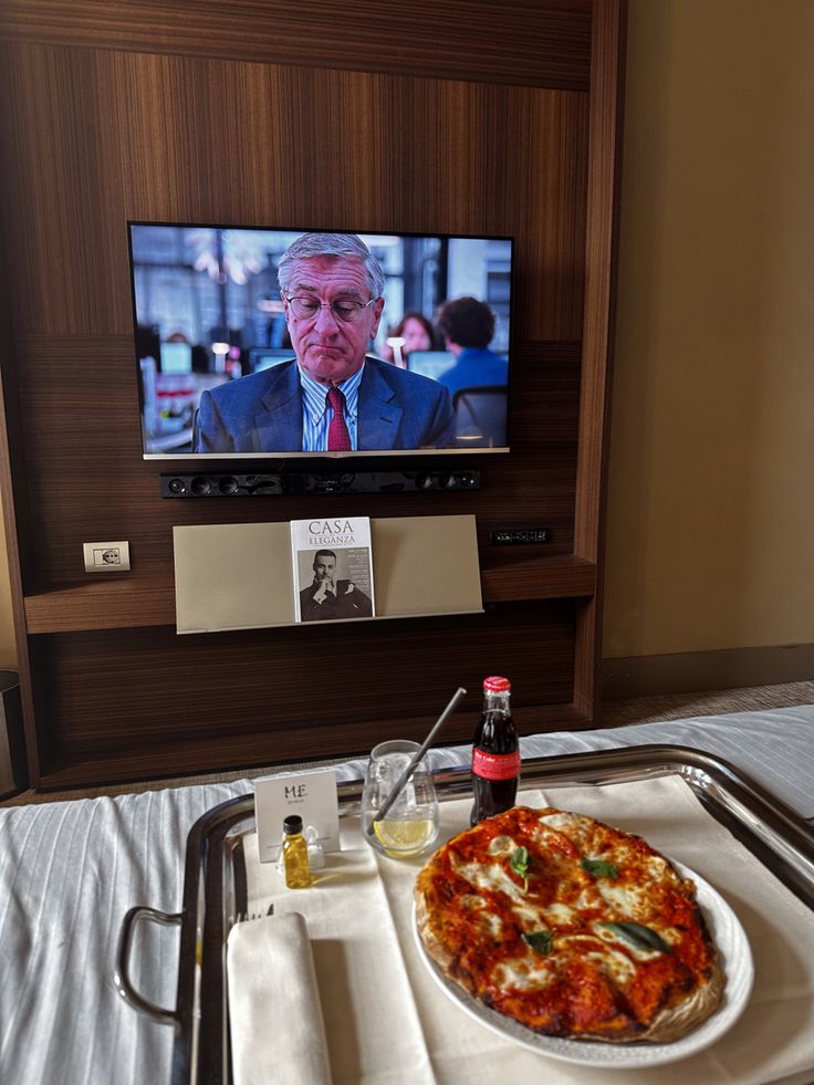 a tray with a pizza and ketchup on it in front of a television