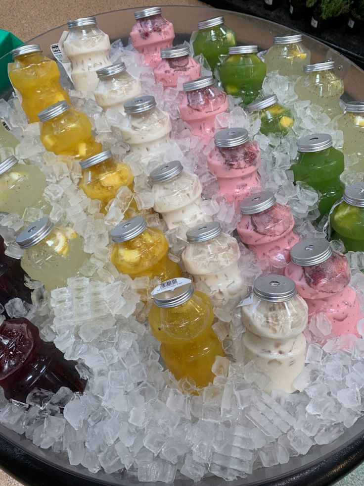 there are many different colored bottles in the ice on this tray with water and jelly