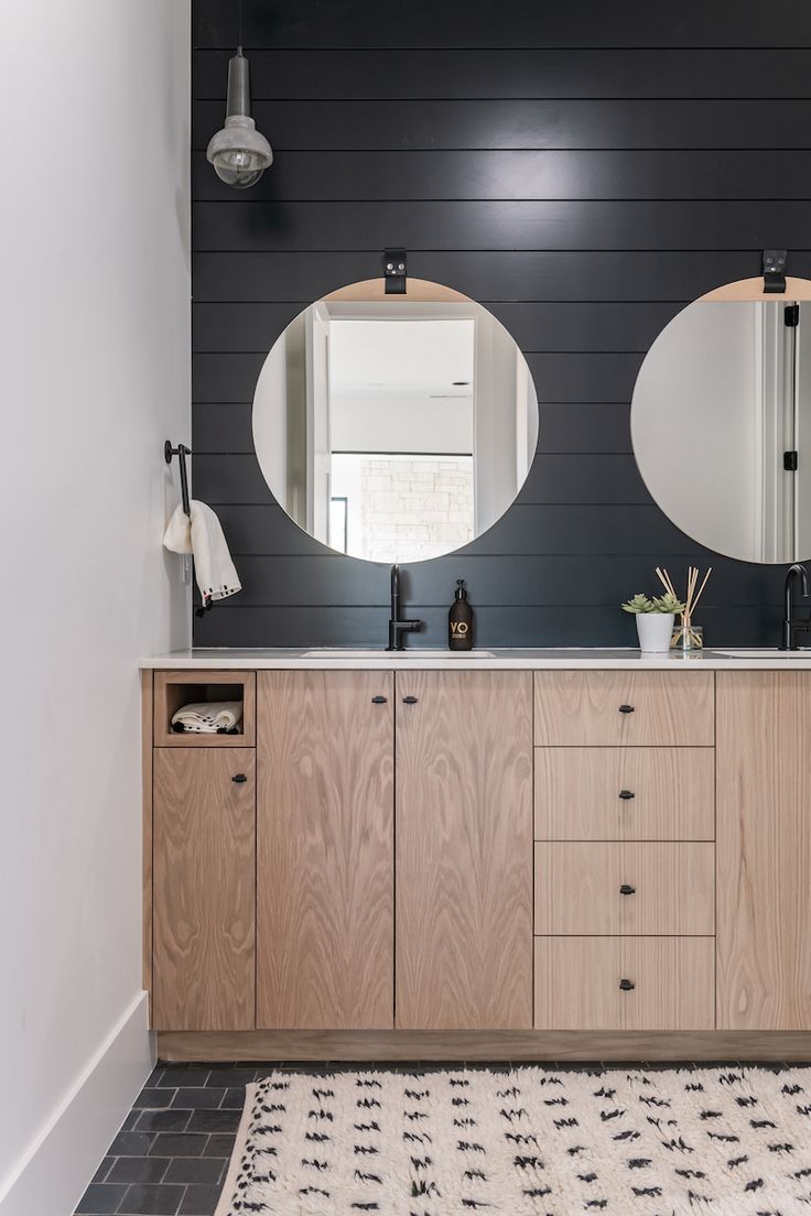 a bathroom with two round mirrors on the wall and a rug in front of it