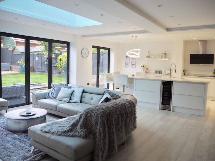 a living room filled with furniture next to a kitchen and an open door leading to a backyard