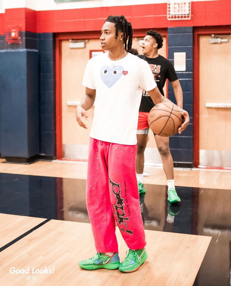 a man standing on top of a basketball court with a ball in his hand and two other men behind him