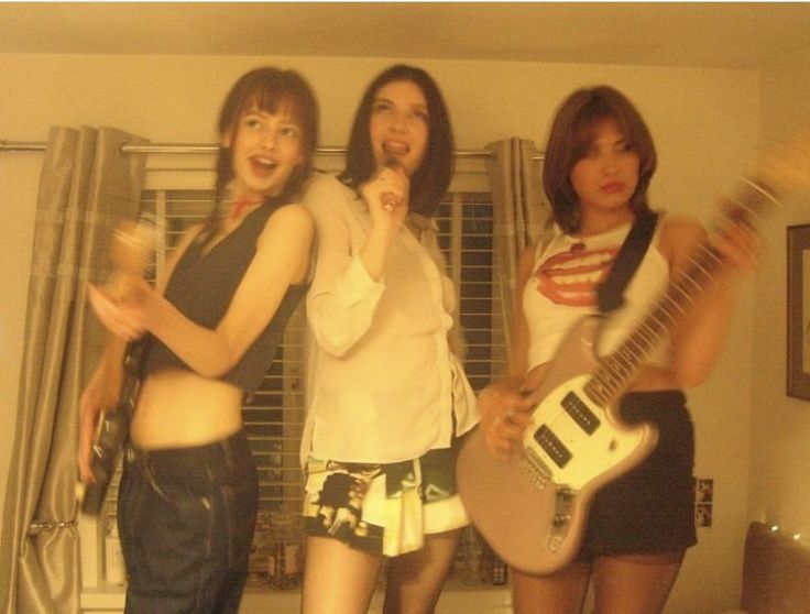 three young women standing next to each other holding guitars