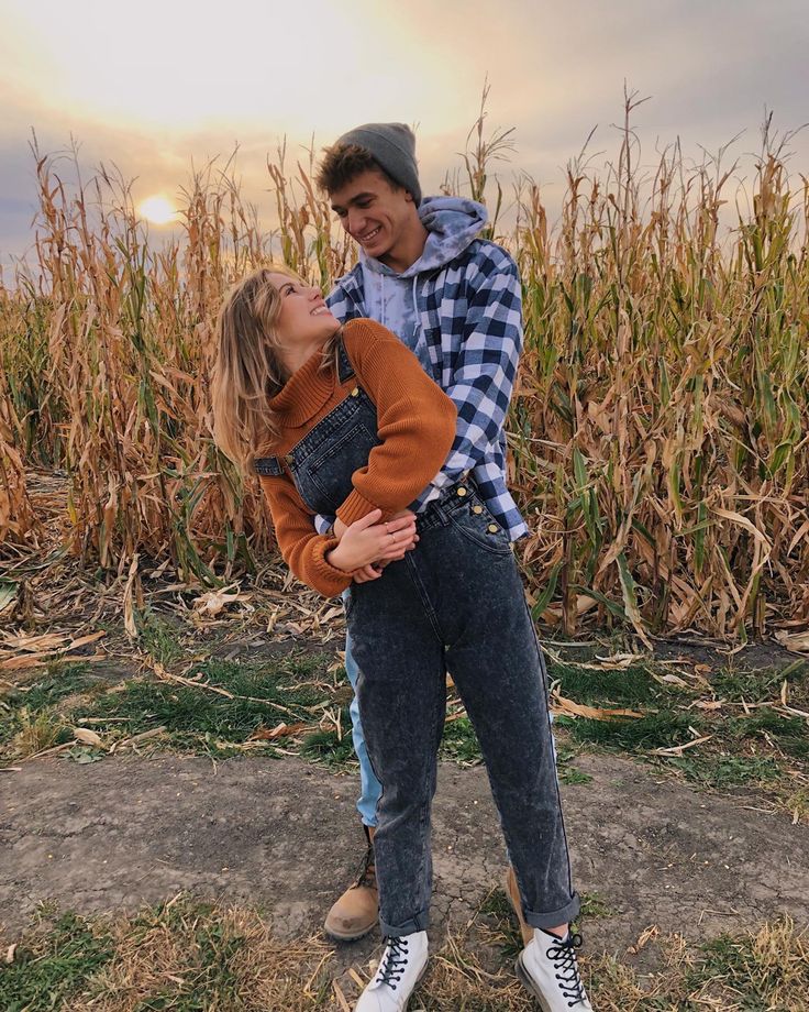 a man and woman standing in front of a corn field