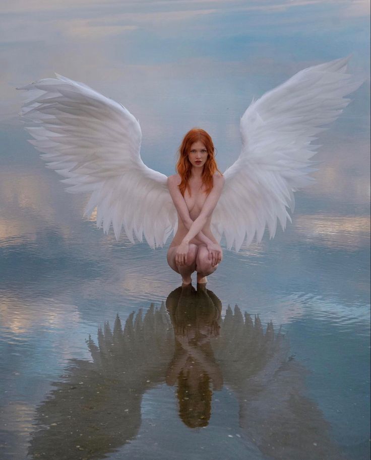 a woman with white wings kneeling in the water