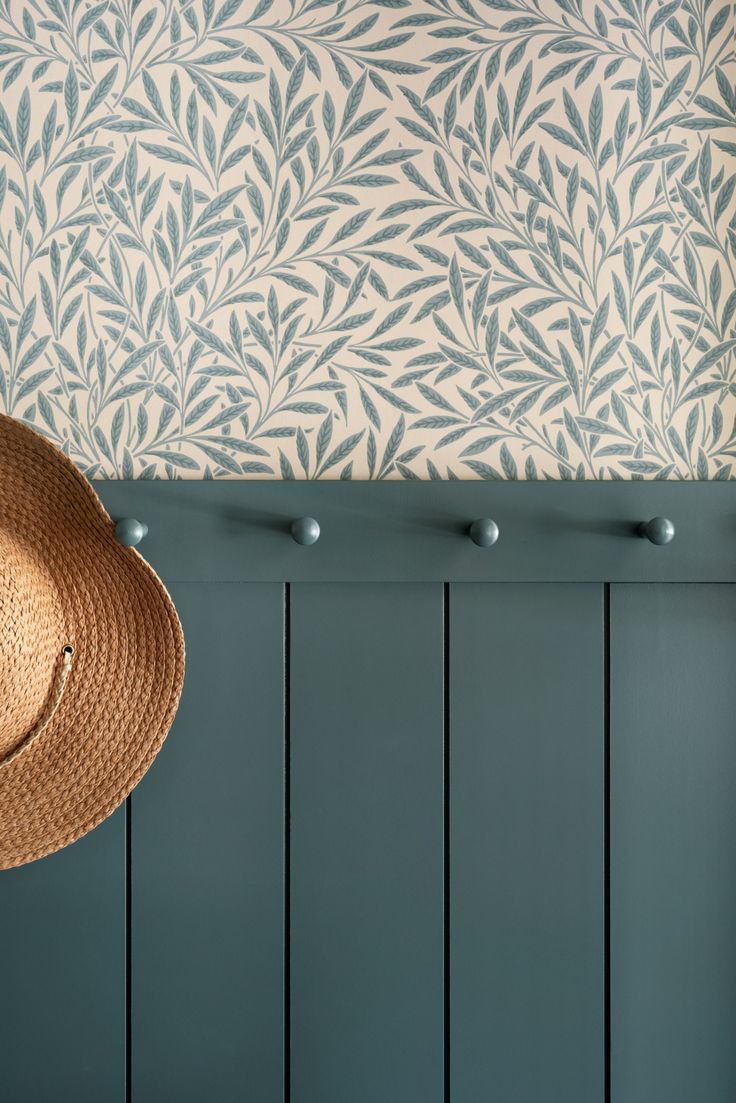 a hat hanging on the side of a wall next to a blue paneled wall