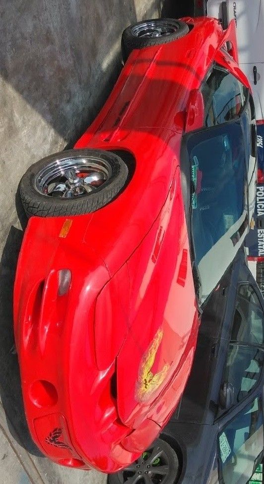 an upside down red car parked next to a building