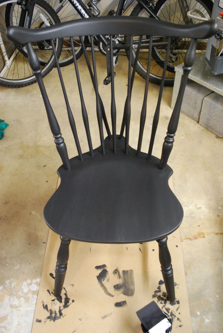 a black chair sitting on top of a piece of wood next to a pair of bicycles