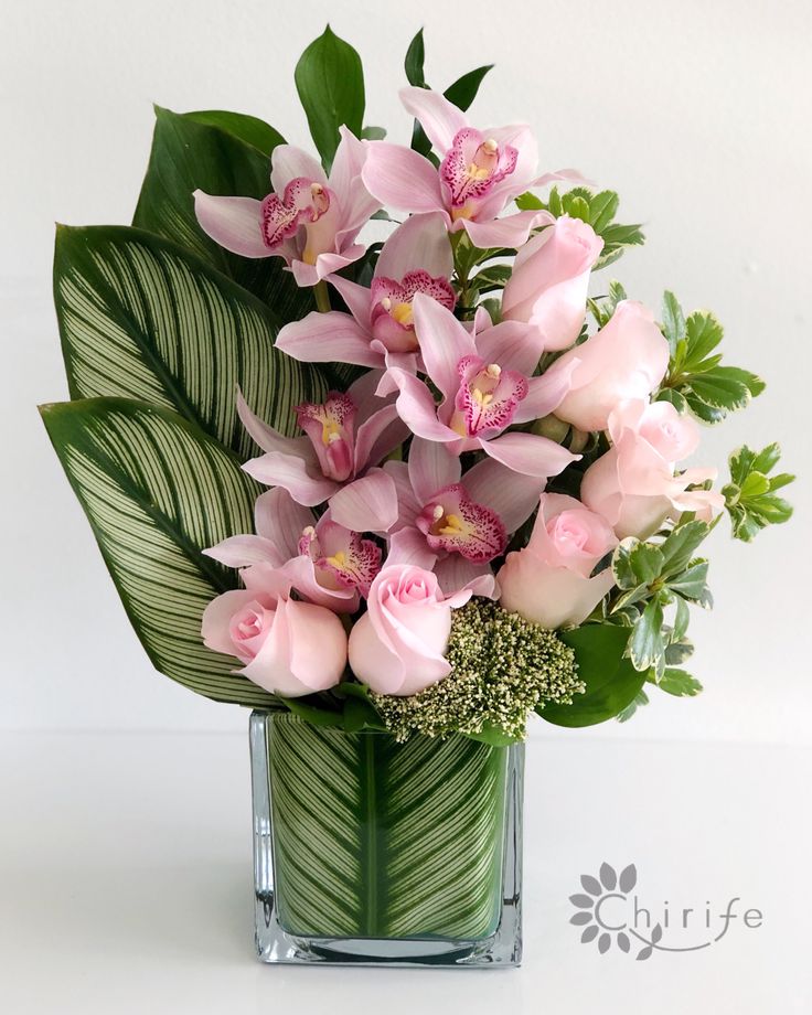 a vase filled with pink flowers and greenery