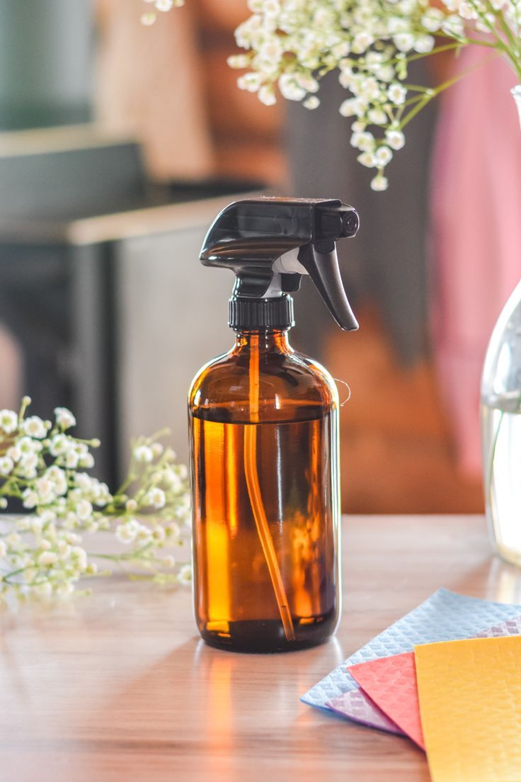 a brown glass bottle with a sprayer on top of it next to some flowers