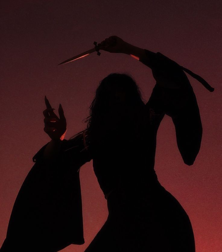 the silhouette of a woman holding a knife in her hand and wearing a black outfit