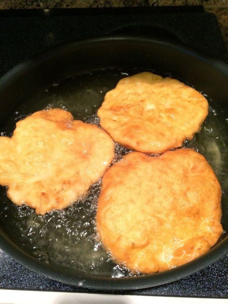 three pieces of fried food cooking in a frying pan on the stove burners