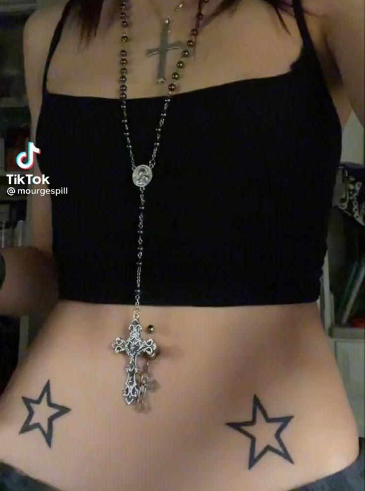 a woman with tattoos on her stomach has a cross and star tattoo on her belly