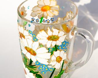 a glass mug with flowers painted on it