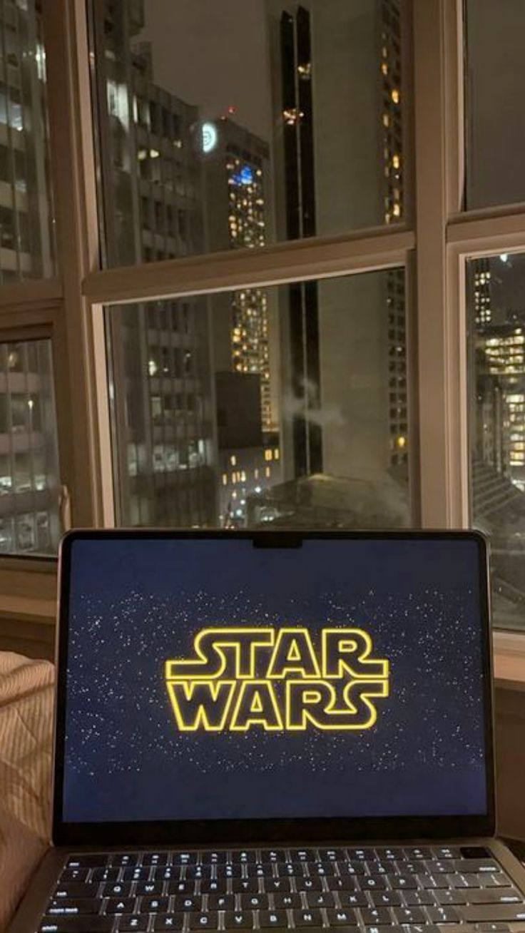 a laptop computer sitting on top of a table in front of a window with the word star wars written on it