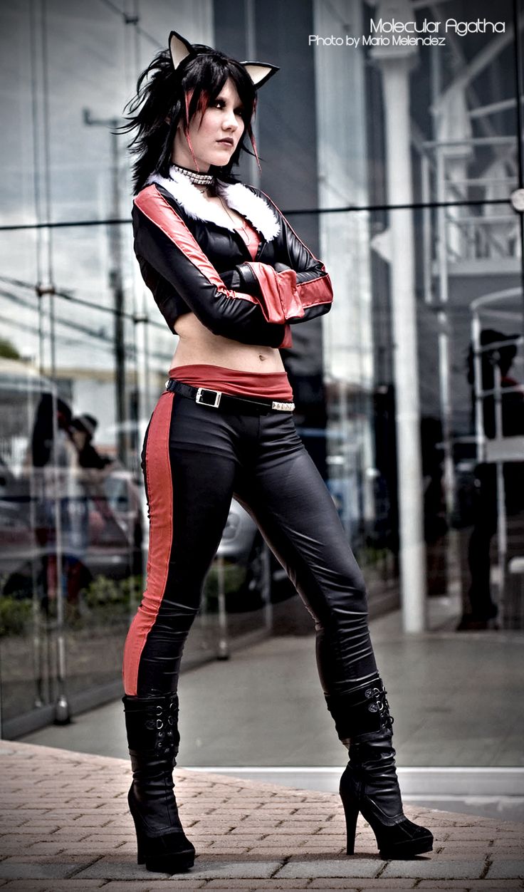 a woman in black and red catsuits posing for the camera with her arms crossed