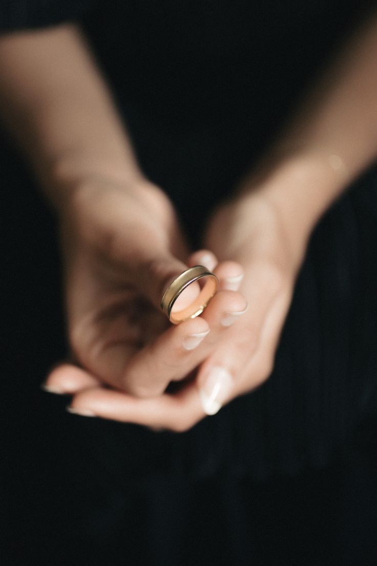 two hands holding wedding rings in each other's palms, with one being held by the other