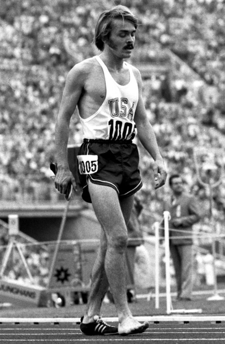 an old photo of a man running on a track in front of a large crowd