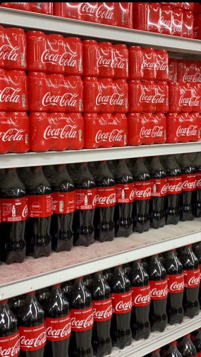 several rows of coca - cola cans on shelves in a grocery store, one is red and the other is black