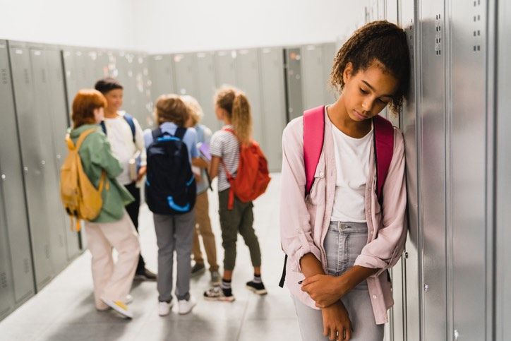 a group of young people standing next to each other in a hallway with lockers