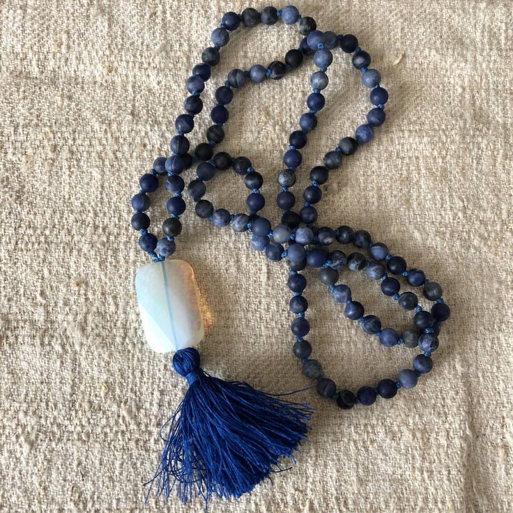 "Malas are a wonderful way to bring your love of crystals and meditation together. And if you can use them as jewelry, even better! This is a hand-made (by me) 108-bead 6mm mala, made with matte denim lapis beads and a rectangular opaline guru bead. It's hand-knotted with nylon cord, with a hand-made silk tassel. Approximately 30\". The beads are slightly smaller than most of the malas you see (which are 8mm) so it makes it small enough that it also works well as a necklace." Bohemian Lapis Lazuli Crystal Necklace For Healing, Adjustable Hand Knotted Mala For Meditation, Adjustable Beaded Mala For Meditation, Adjustable Hand Knotted Beads For Meditation, Artisan 108 Beads For Meditation, Adjustable Natural Stones Mala For Meditation, Blue Mala With 8mm Beads For Meditation, Hand Knotted Adjustable Spiritual Beads, Bohemian 108 Beads For Meditation