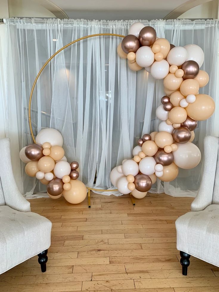 a balloon arch with white, gold and silver balloons in the shape of an o