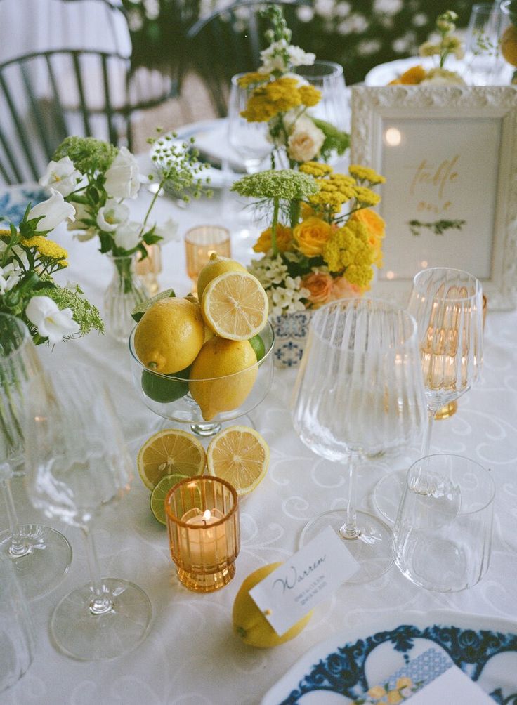 a table topped with plates and glasses filled with lemons