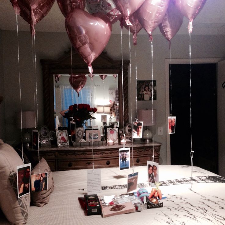 balloons are hanging from the ceiling above a bed with pictures on it and photos pinned to them