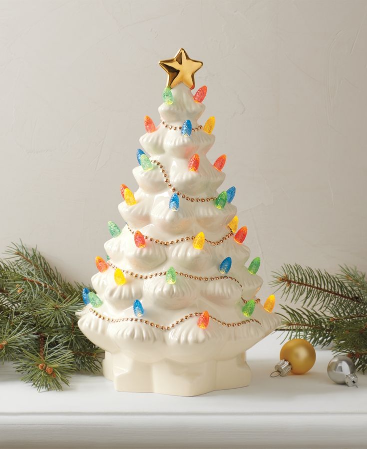 a white ceramic christmas tree with lights and ornaments