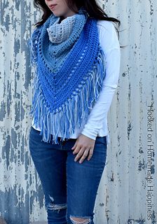 a woman wearing a blue crocheted shawl with fringes on the sides