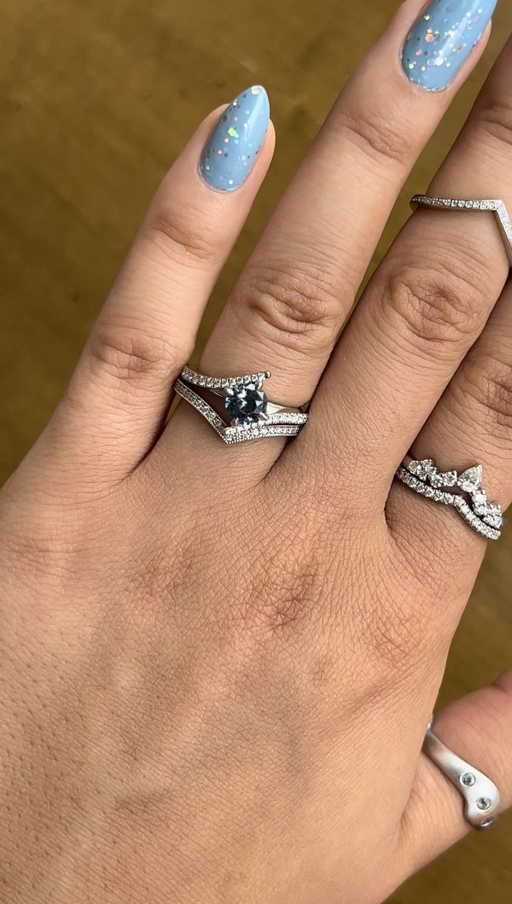 a woman's hand with three different rings on it and one has blue nail polish