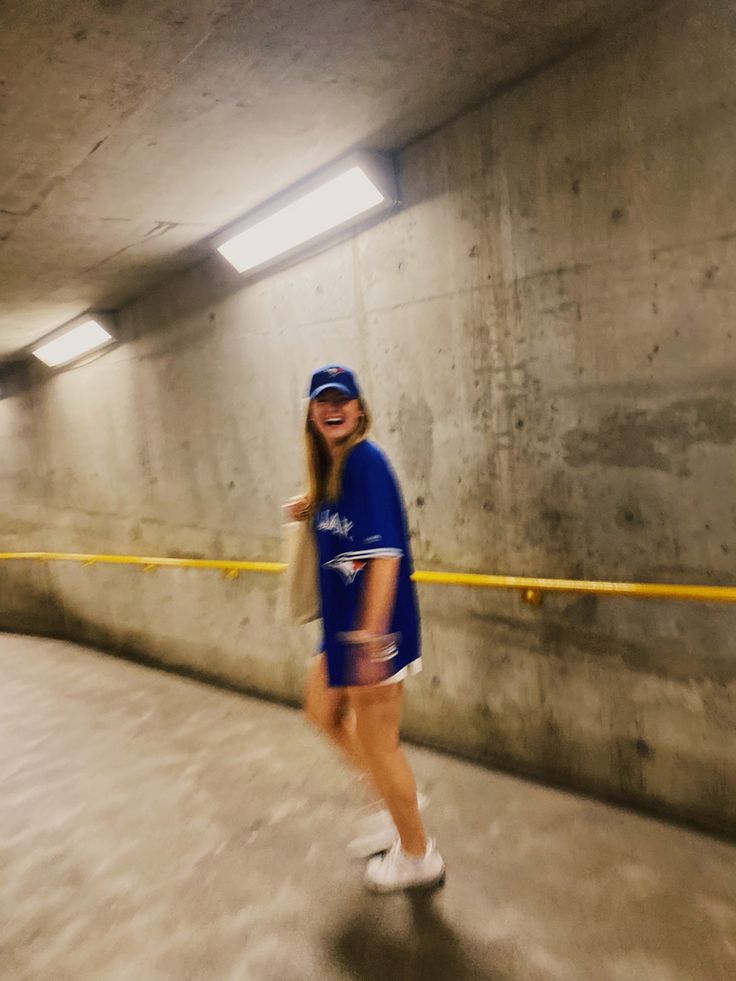 a woman in a blue shirt and white shorts is standing in a tunnel with yellow caution tape