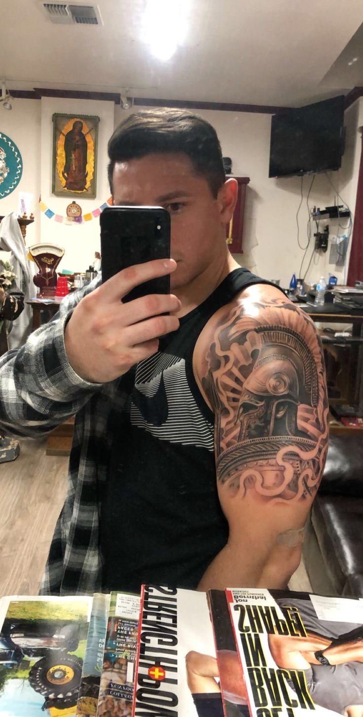 a man is taking a selfie with his cell phone while wearing a sleeve tattoo