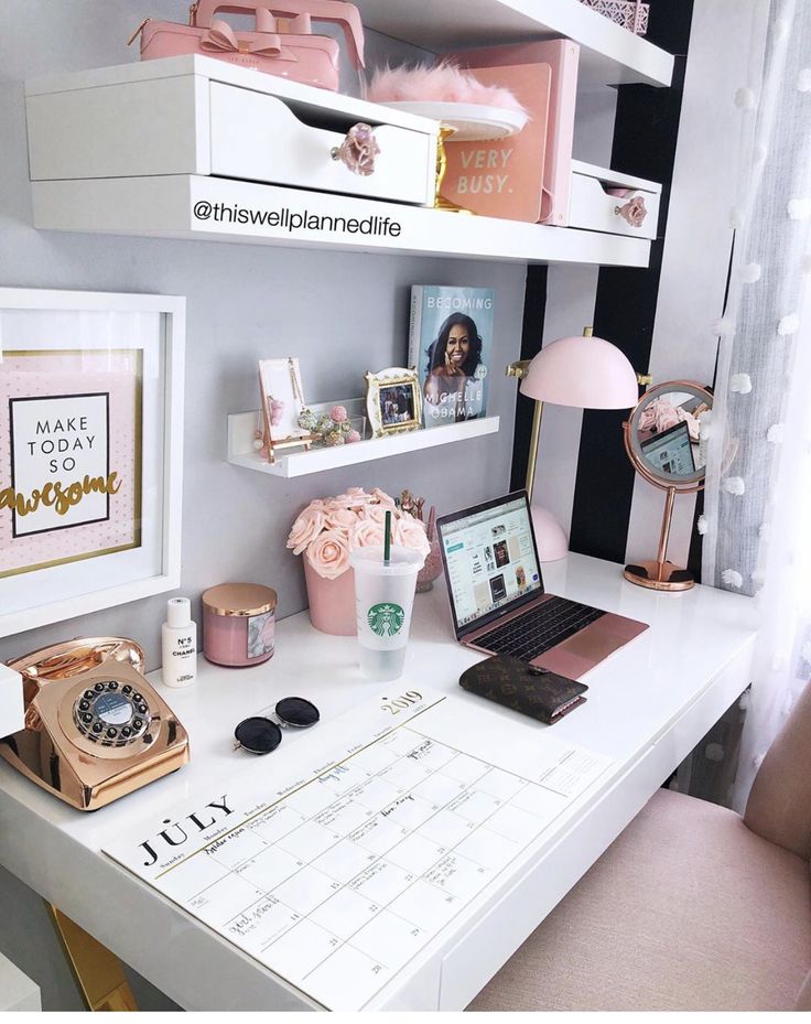 a white desk topped with a laptop computer sitting next to a pink flower filled vase