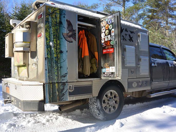 a truck is parked in the snow with its doors open and clothes hanging out to dry