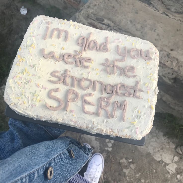 someone holding up a cake with writing on it