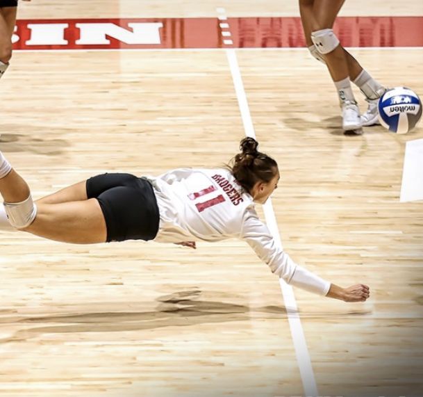 a female volleyball player dives for the ball