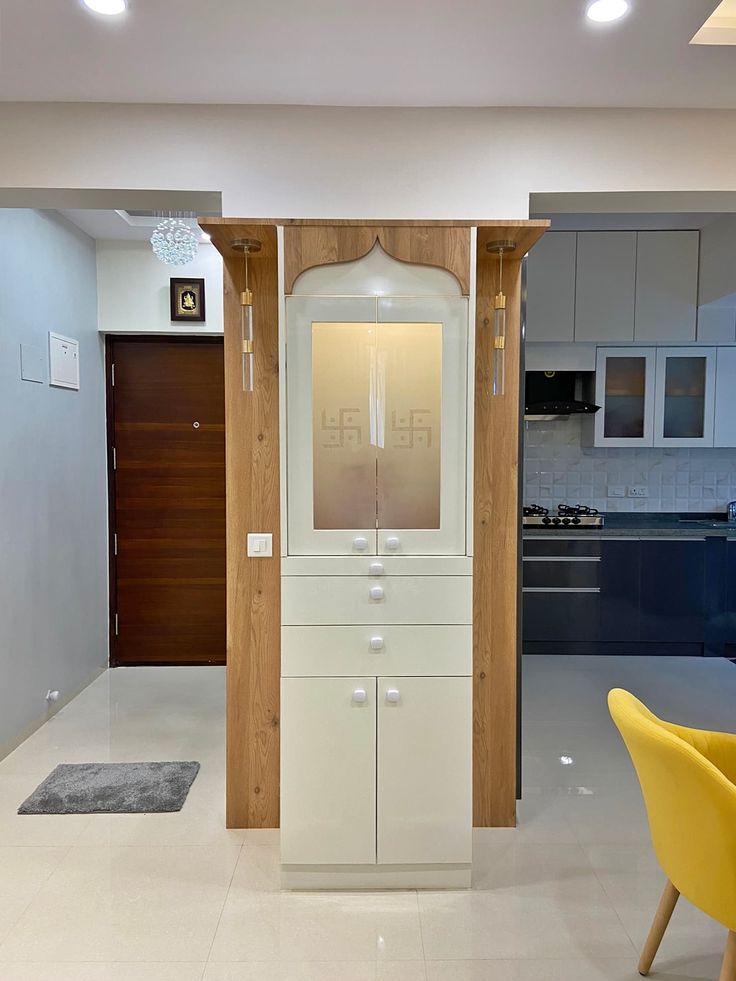 a white cabinet sitting in the middle of a room next to a yellow chair and table