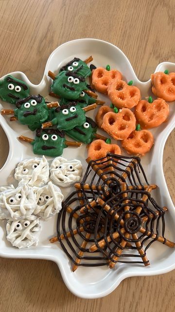 halloween treats are arranged in the shape of a monster and spider web on a white platter