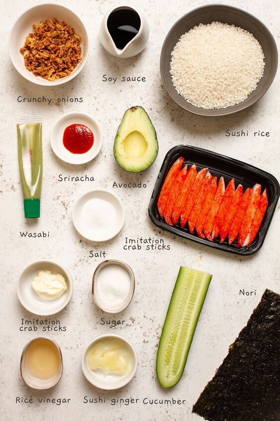 the ingredients to make sushi are displayed on a white counter top, including carrots, rice, cucumbers, and sauce