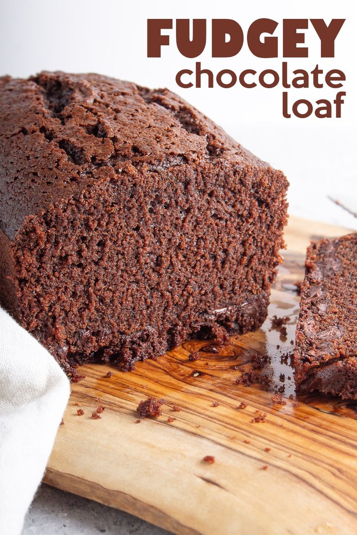 a loaf of fudgey chocolate loaf sitting on top of a wooden cutting board