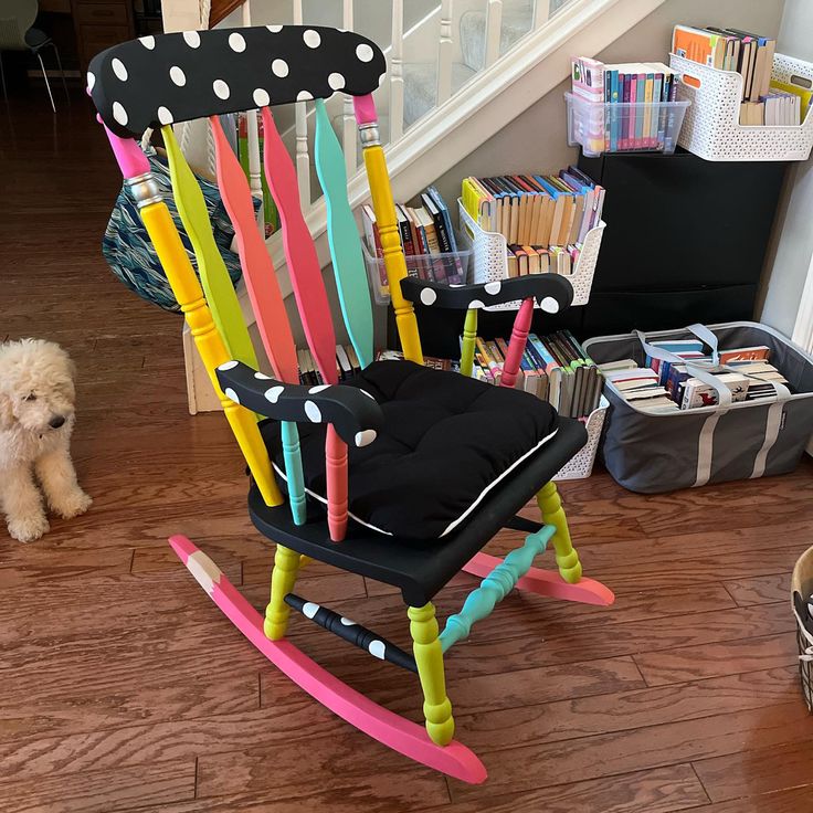 a dog sitting in front of a colorful rocking chair with polka dots on it's seat