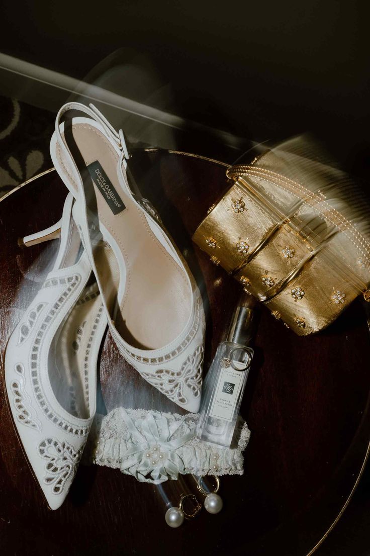 wedding shoes and purse sitting on top of a wooden table next to a gold purse