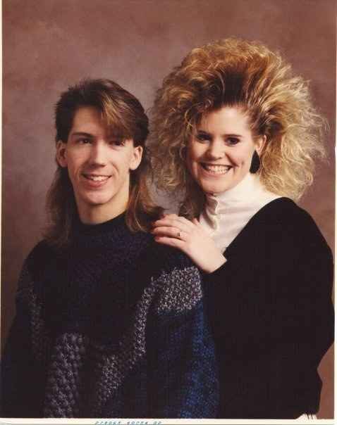 two people standing next to each other in front of a brown wall and one person with blonde hair