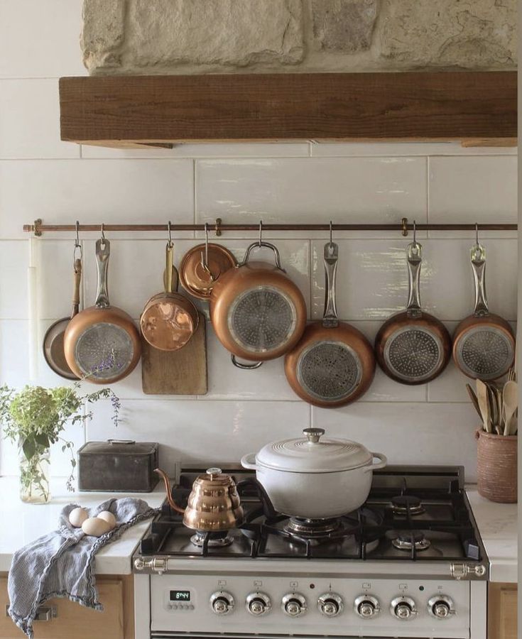 pots and pans are hanging on the wall above an oven