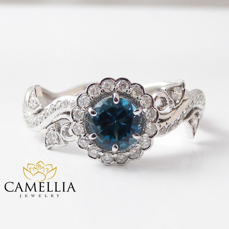 a blue and white diamond ring sitting on top of a white surface with the words camellia written below it