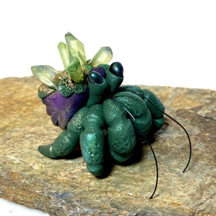 a small green toy sitting on top of a rock