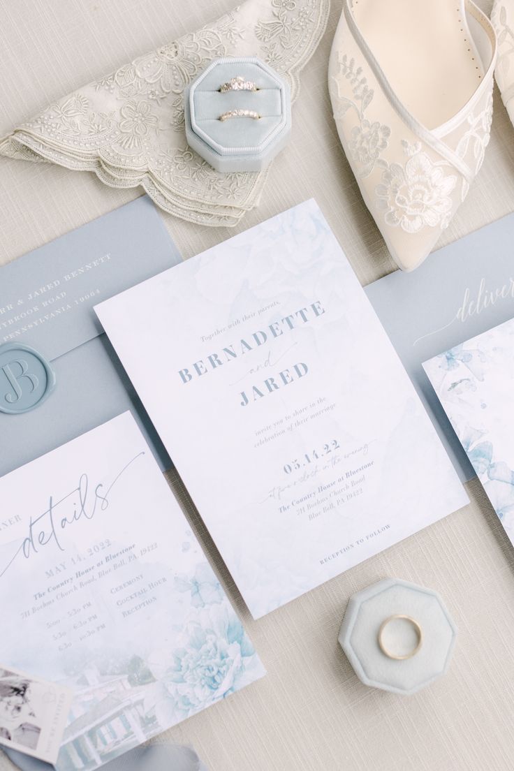 the wedding stationery is laid out on top of the bride's dress and shoes